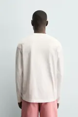 Camiseta de manga larga color blanco roto, corte relajado (relaxed fit) con cuello redondo y texto estampado en negro en el pecho que dice "CUPID APPROVED".