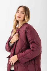 Chaqueta acolchada de color negro con diseño de costuras onduladas. Presenta cuello redondo, cierre frontal con botones a presión y dos bolsillos frontales tipo cargo con solapa y detalle de hebilla. Posee un corte holgado y mangas largas.