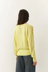 Sweater amarillo calado de manga larga con cuello redondo, puños y cintura elastizados.