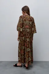 Vestido largo de silueta amplia y caída fluida, con estampado y recortes fruncidos que aportan movimiento. Presenta escote con abertura, cierre frontal con botones y mangas largas de volumen amplio con puños elastizados.