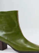 Botas de caña media color marrón, confeccionadas en cuero con acabado brillante. Presentan punta cuadrada, taco de madera y un distintivo bordado decorativo en color rojo que recorre el empeine hasta la punta.