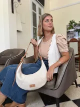 Cartera tipo hobo de cuero color crudo con correa de cuero marrón.