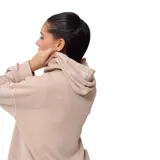 Canguro beige con capucha, cordones ajustables, bolsillo tipo canguro y logo de la marca en el pecho.