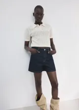 Short de denim azul oscuro con diseño de cinco bolsillos, tiro medio y cierre frontal de cremallera y botón.