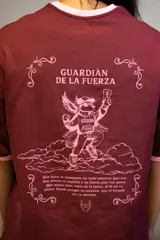Remera oversize color bordó con cuello y puños de rib de color rosado. Estampado frontal en rosado con el texto "GUARDIÁN DE LA FUERZA" y otros símbolos.
