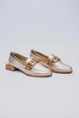 Mocasines de cuero en tono metalizado dorado, con detalle de aplique metálico en el empeine y taco cuadrado bajo de madera.