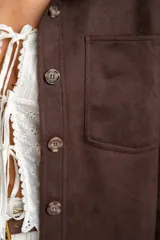 Sobrecamisa de gamuza sintética en color marrón chocolate, con corte oversize, cuello camisero, cierre frontal con botones y bolsillos frontales tipo parche.