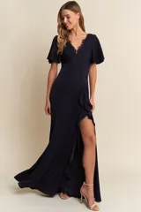 Vestido largo de fiesta color azul marino, con escote en V adornado con encaje, mangas cortas con abertura y falda con tajo lateral decorado con volados.