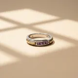 Anillo de diseño bicolor en plata y oro, con una hilera central de cuatro circonias cuadradas de color violeta.