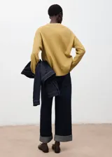 Sweater de punto fino en color mostaza, con cuello redondo y diseño oversize de manga larga. Presenta un acabado de canalé en los puños y el ruedo.
