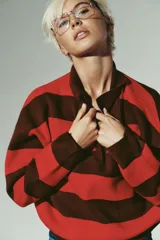 Jersey de punto a rayas horizontales en color marrón y rojo, con cuello polo y cierre frontal parcial, de manga larga y diseño holgado.