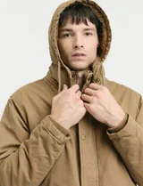 Campera de abrigo estilo parka, color verde oscuro, con capucha desmontable, cierre frontal con botones y cremallera, múltiples bolsillos frontales y en la manga.