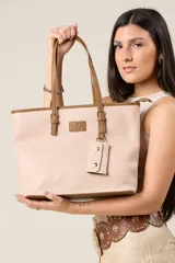 Cartera tote color rosa pálido de ecocuero texturado con detalles en tono camel. Tiene doble asa de hombro, logo de la marca grabado en el frente, llavero colgante y múltiples compartimentos interiores.