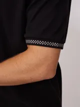 Remera polo blanca de corte regular, con cuello y mangas con ribete a cuadros en contraste. Presenta un pequeño logo bordado en el pecho.