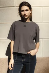 Remera de algodón color gris oscuro, con corte boxy y cuello redondo. Presenta un pequeño logo bordado en el pecho.