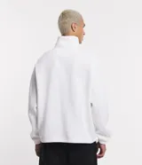 Buzo de corte holgado tipo ballon, color marrón oscuro, con cuello alto y cierre frontal parcial. Presenta mangas largas con puños elásticos y cordón ajustable en el ruedo.