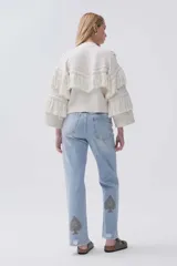 Jean celeste de calce recto y tiro medio-alto, con bordado de picas en tonos amarronados, lavado claro y ruedo desflecado.