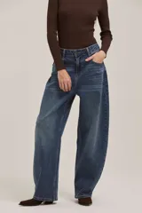Jean de corte wide leg y tiro alto, con diseño de pierna curva o tipo barril, en tono azul medio con efecto lavado.