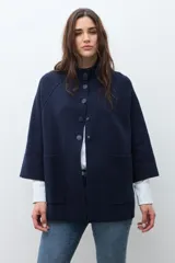 Chaqueta corta de tejido de punto color azul marino, con cuello mao abotonado y mangas tres cuartos. Presenta bolsillos frontales amplios.