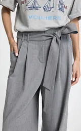 Pantalon sastrero de tiro alto en color gris, con diseño de pierna ancha y corte relajado. Presenta pliegues frontales, bolsillos laterales y un cinturón del mismo tejido para ajustar en la cintura.