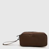 Cartuchera rectangular de diseño minimalista, color marrón, con cierre superior y correa de muñeca extraíble. Presenta el logo de la marca estampado en el frente.