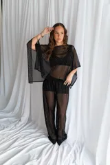 Blusa de tul negro semitransparente con diseño de mangas murciélago amplias y aplicación de pequeños puntos brillantes plateados distribuidos por toda la prenda.