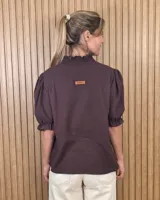 Blusa marrón oscura de manga corta abullonada con puños elastizados, escote en V y cuello alto con volados.