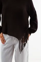 Sweater negro de tejido acanalado, con cuello redondo y un detalle asimétrico en el ruedo inferior con flecos largos.