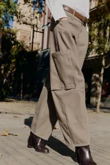 Pantalón cargo de tiro alto color marrón topo, con pierna ancha y holgada que se estrecha hacia el tobillo. Presenta bolsillos delanteros, bolsillo de plastrón lateral y falso bolsillo de vivo en la espalda.