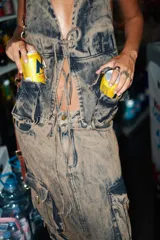 Top tipo chaleco de denim ahumado color azul, con escote halter, cierre frontal con lazo y dos bolsillos tipo cargo con estribos de bronce.