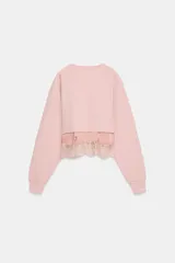 Sudadera crop de algodón con cuello redondo y manga larga. Presenta un diseño de doble capa con un top interior satinado y un bajo decorado con encaje a tono.