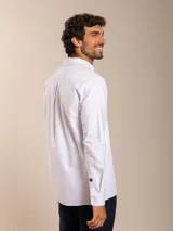 Camisa blanca de corte clásico con cuello abotonado, manga larga y bolsillo en el pecho.