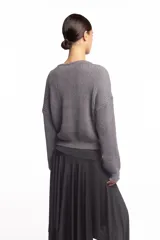 Buzo de punto inglés grueso en color gris melange, de corte amplio con hombros caídos y mangas largas, con sutil bordado de la marca en el pecho.