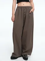 Pantalón de corte amplio y holgado en color verde oliva, con cintura elástica y detalle de botones frontales. Incluye bolsillos laterales funcionales.
