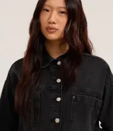 Camisa de jean negra con abotonado delantero, cuello solapa, mangas largas, recortes y bolsillos grandes en el pecho.