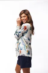 Camisa de manga larga con estampado floral en tonos azules, verdes, naranjas y amarillos sobre fondo blanco.