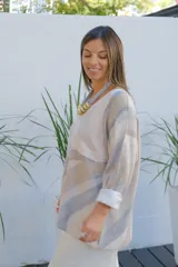 Sweater de punto con diseño de ondas en tonos beige y gris, de corte amplio, escote en V y mangas largas con puños vueltos.