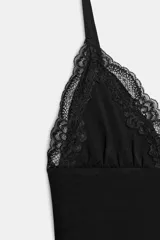 Vestido mini negro con escote en pico y tirantes finos ajustables. Presenta detalles de encaje combinado a tono en el escote y en el ruedo.