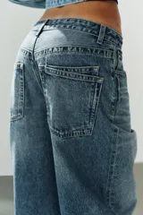 Jeans de tiro medio con diseño baggy, de pernera ancha y corte holgado. Cuenta con cinco bolsillos, trabillas para cinto y cierre frontal con cremallera y botón metálico.