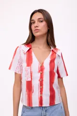 Blusa de manga corta con cuello camisero y botones, con estampado de rayas verticales rojas y texto manuscrito.