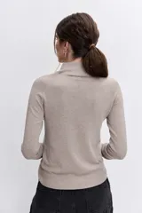 Jersey de punto fino en color negro, con cuello alto y mangas largas ajustadas.