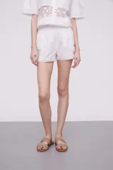 Short blanco de algodón con cintura elástica y detalles de encaje crochet en los laterales y el ruedo.