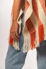 Ruana tejida a mano en Uruguay, con lana merino color crudo y franjas verticales color terracota.