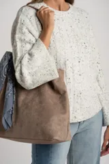 Sweater de punto color blanco roto con efecto tweed (pequeñas motas negras), cuello redondo y manga larga acampanada. Presenta un tejido texturado con trenzas verticales.