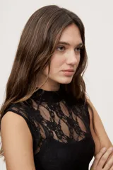 Top de encaje blanco con cuello alto y diseño sin mangas, de corte ajustado.