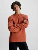 Remera de manga larga con cuello redondo y puños de canalé, confeccionada en punto gofrado de algodón. Presenta una insignia con el logo de Calvin Klein en la manga.