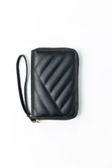 Billetera pequeña de color negro con diseño acolchado y costuras diagonales. Cuenta con cierre perimetral y una correa de muñeca extraíble.