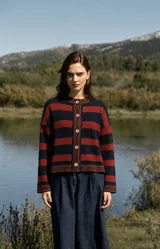 Cardigan de punto con diseño de rayas horizontales en azul marino, rojo y marrón, con cuello redondo y cierre frontal de botones. Presenta detalles tejidos decorativos en los bordes y puños.