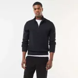 Sweater negro de punto grueso con cuello chimenea y cierre parcial con cremallera. Presenta hombros con costura marcada y puños y cintura acanalados.