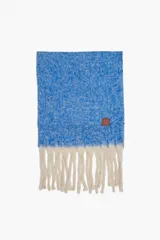 Bufanda rectangular de tejido de punto con textura jaspeada en color azul y flecos largos en color crudo en los extremos. Cuenta con una etiqueta de cuero sintético con logo en una de las esquinas.